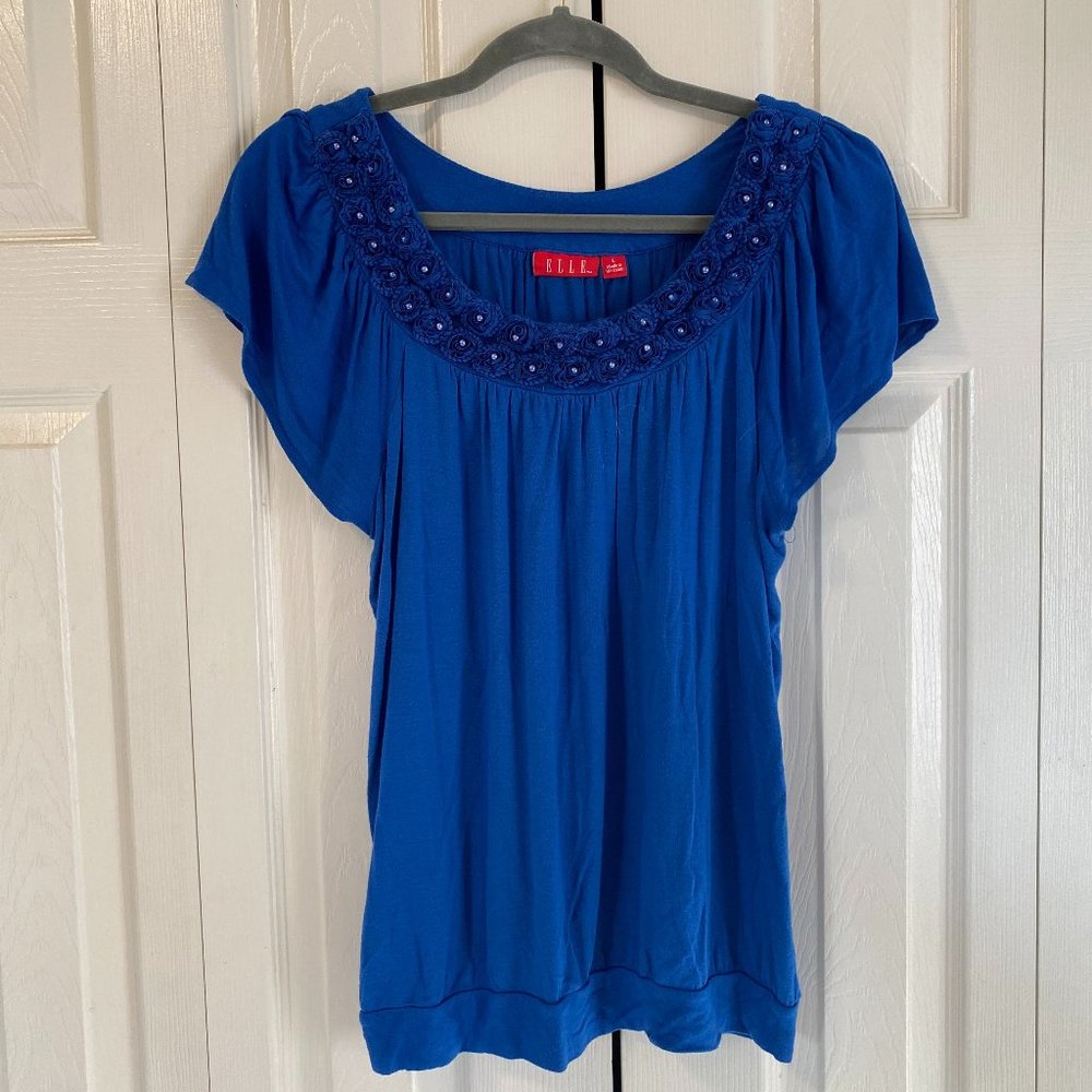 Elle large blue sleeveless shirt with flower pattern on top.